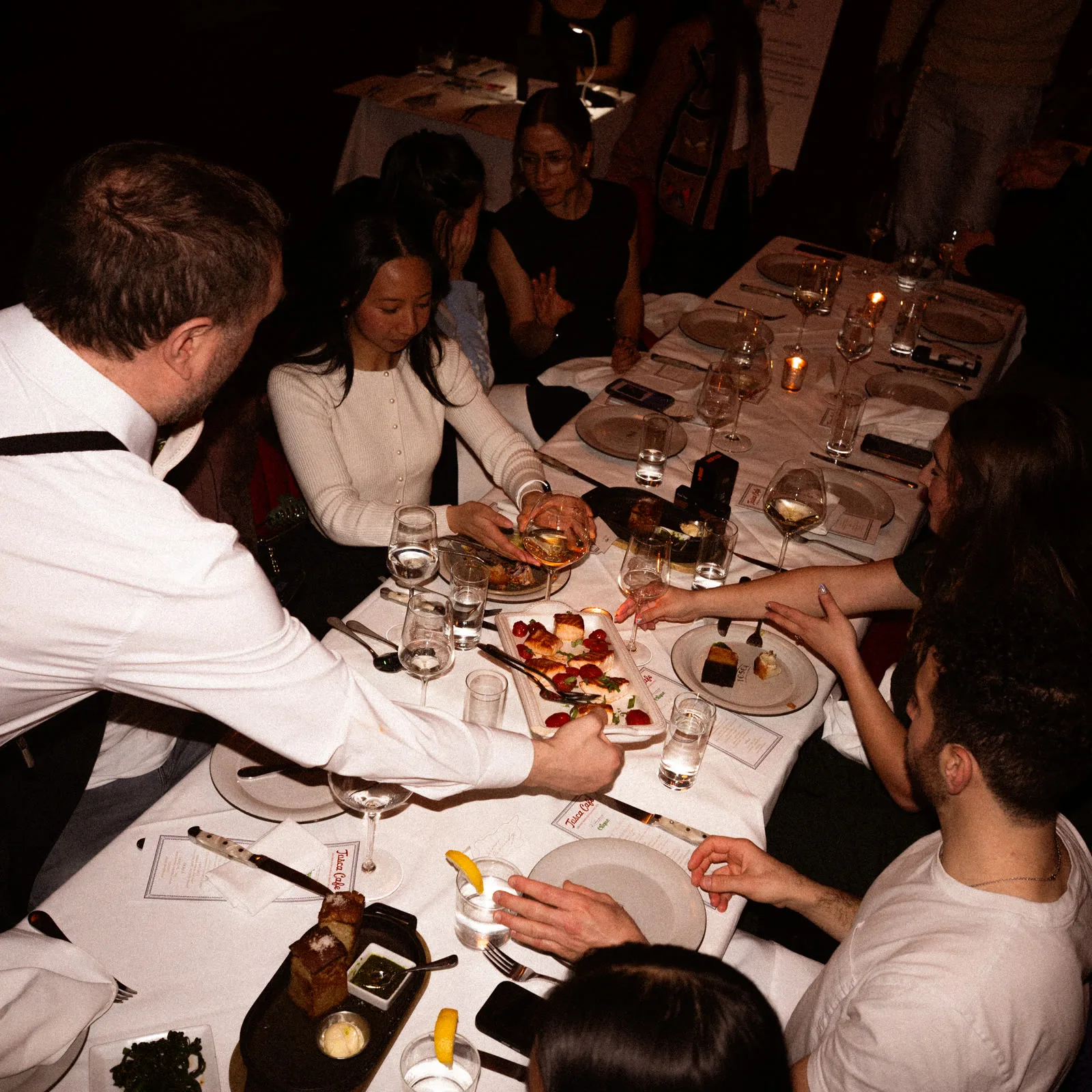 Guests seated around a long table as shared courses are served at a Redamancy dinner.